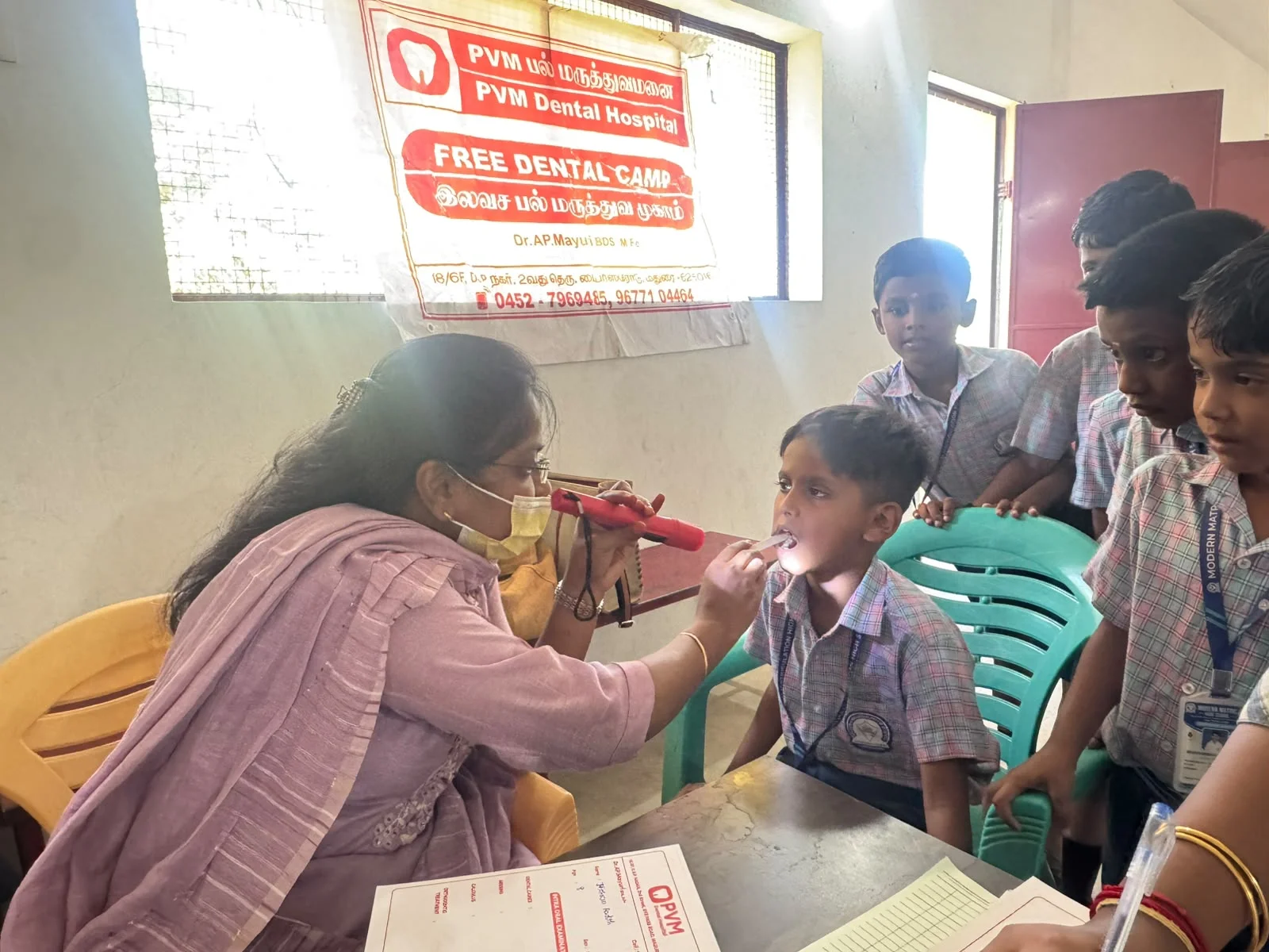 Dr. Mayuri AP examining students with dental pen torch at camp
